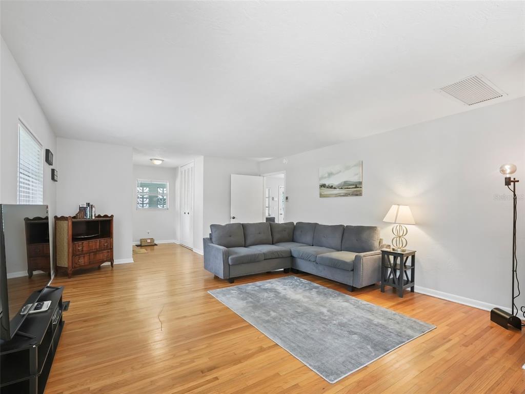 A living room features a grey sectional sofa, hardwood floors, and a grey area rug — 1520 NE 12TH STREET, OCALA, FL
