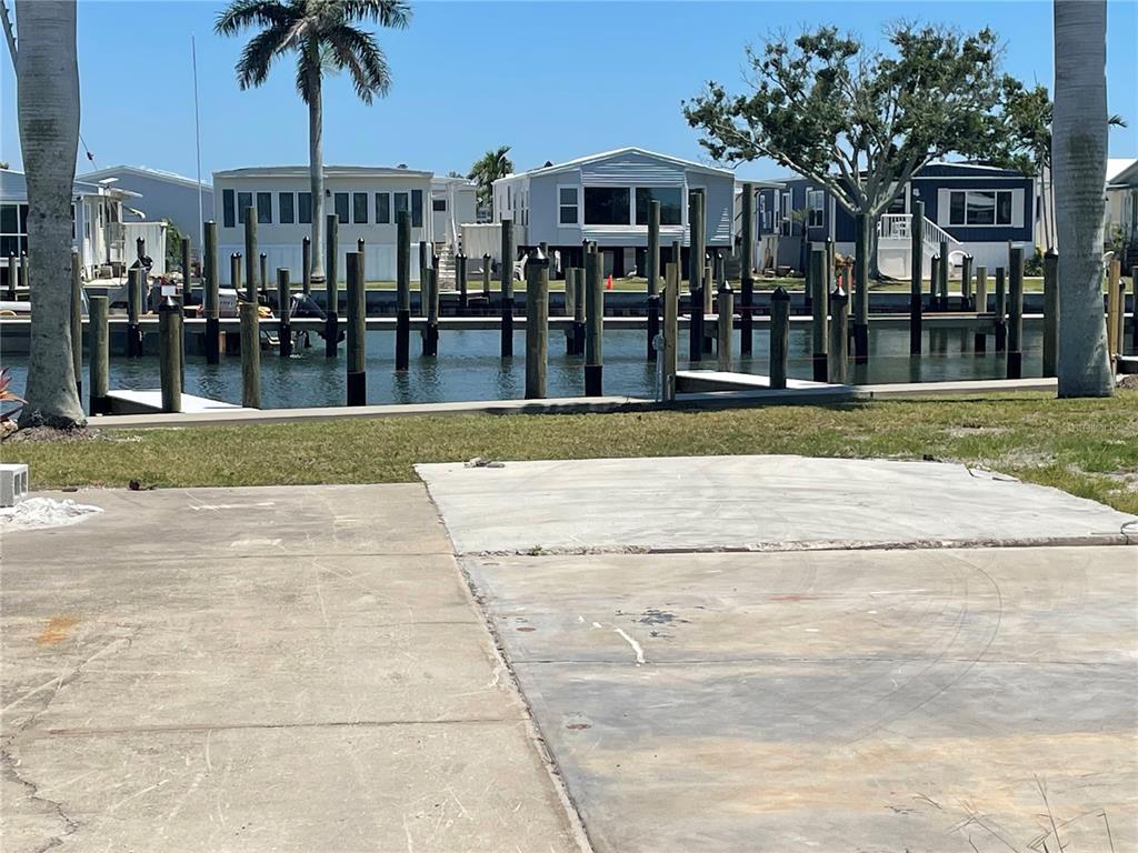 A concrete pad sits in the foreground overlooking a canal with numerous wooden boat pilings — 3710 GULF OF MEXICO DRIVE UNIT G12, LONGBOAT KEY, FL