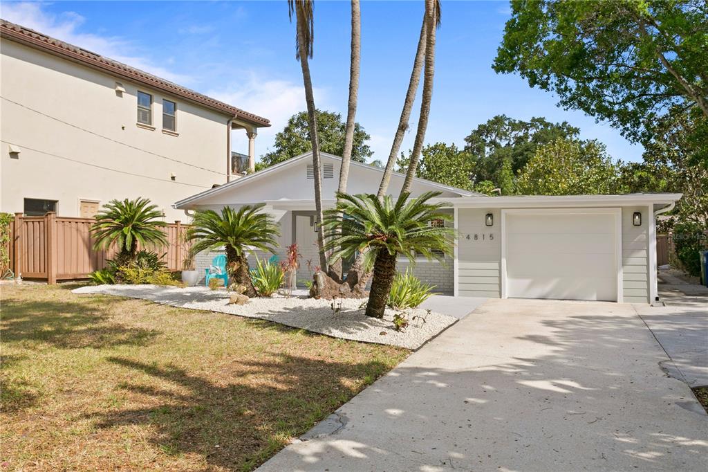 A single-story house with a white exterior, a garage, and palm trees in the front yard — 4815 W SAN RAFAEL STREET, TAMPA, FL