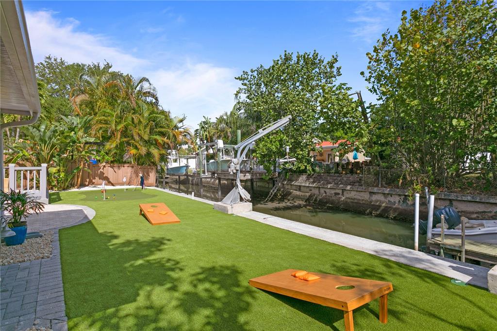 A backyard with artificial turf, a putting green, cornhole boards, and a canal boat lift — 4815 W SAN RAFAEL STREET, TAMPA, FL