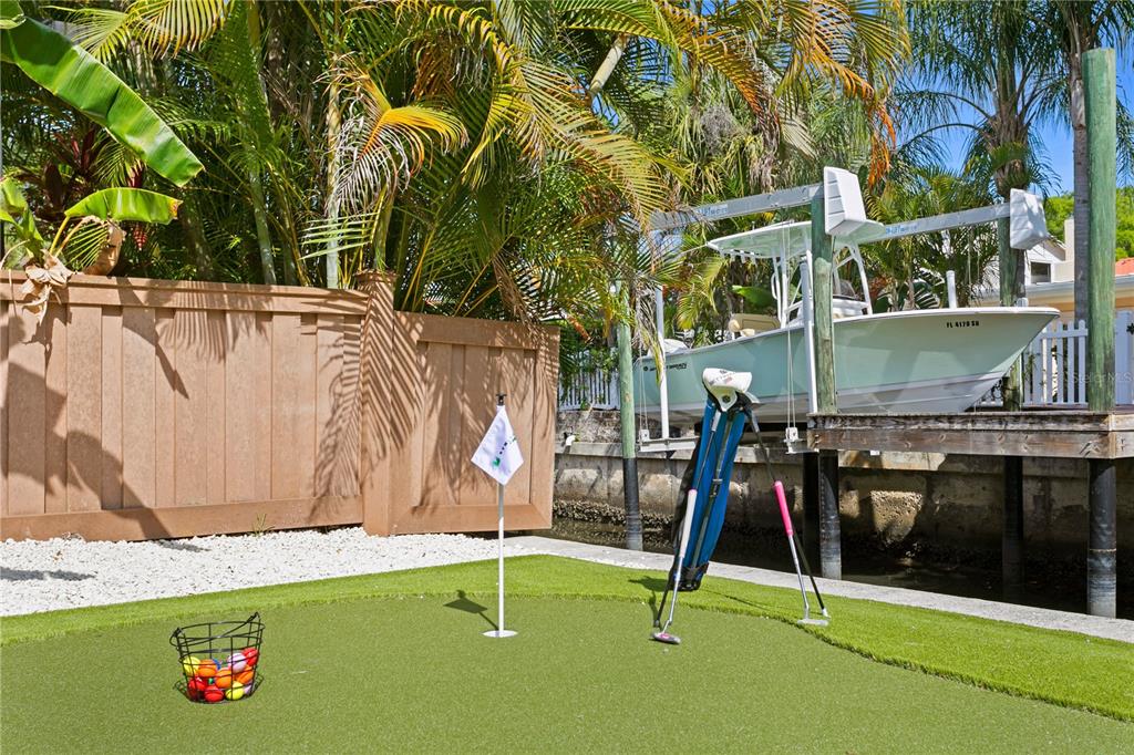 A backyard putting green with a golf bag and ball basket sits beside a boat lift — 4815 W SAN RAFAEL STREET, TAMPA, FL