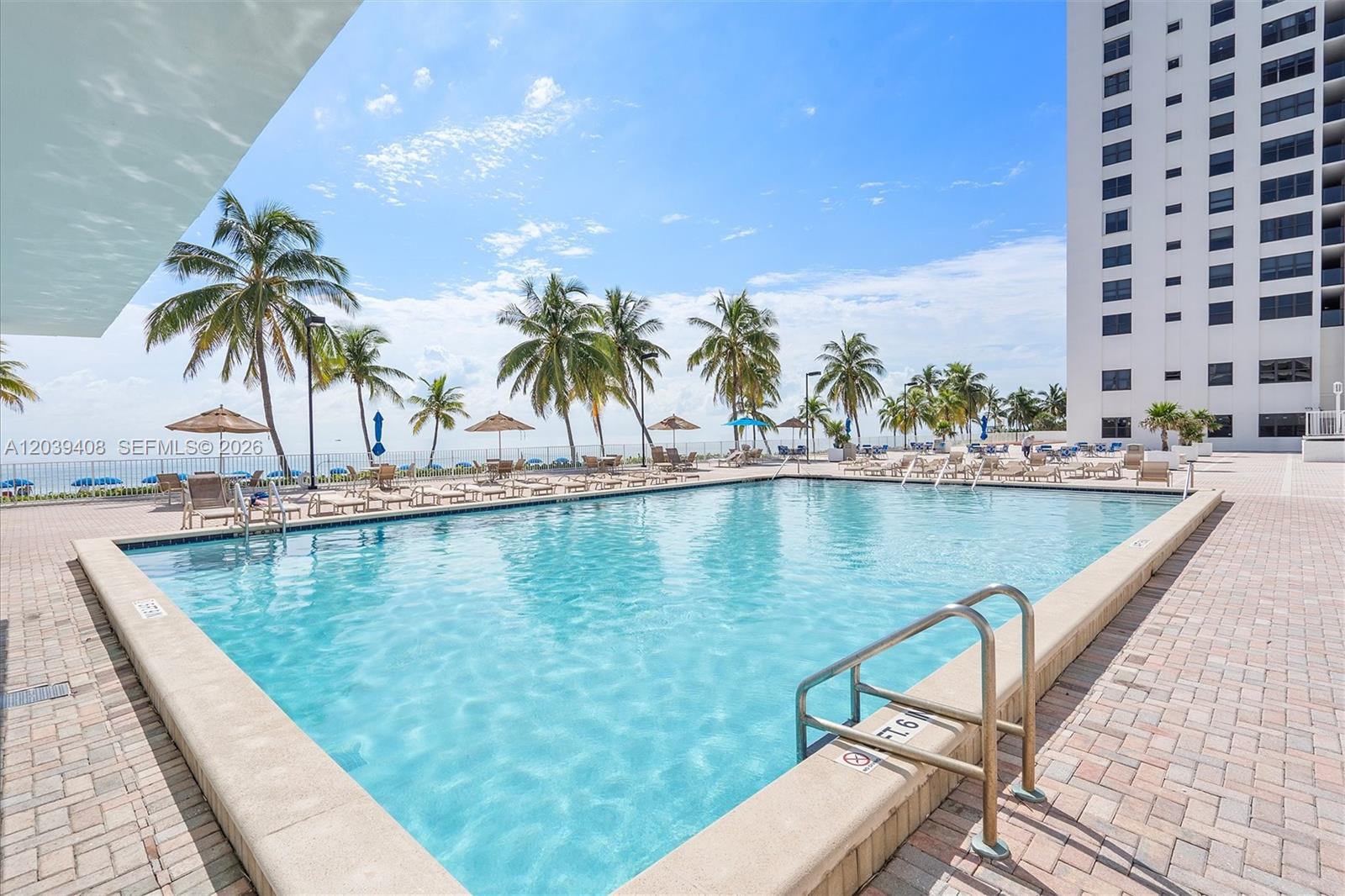 A rectangular swimming pool is surrounded by a paved deck with lounge chairs and palm trees — 2301 S Ocean Dr # 1406, Hollywood FL 33019, HOLLYWOOD, FL