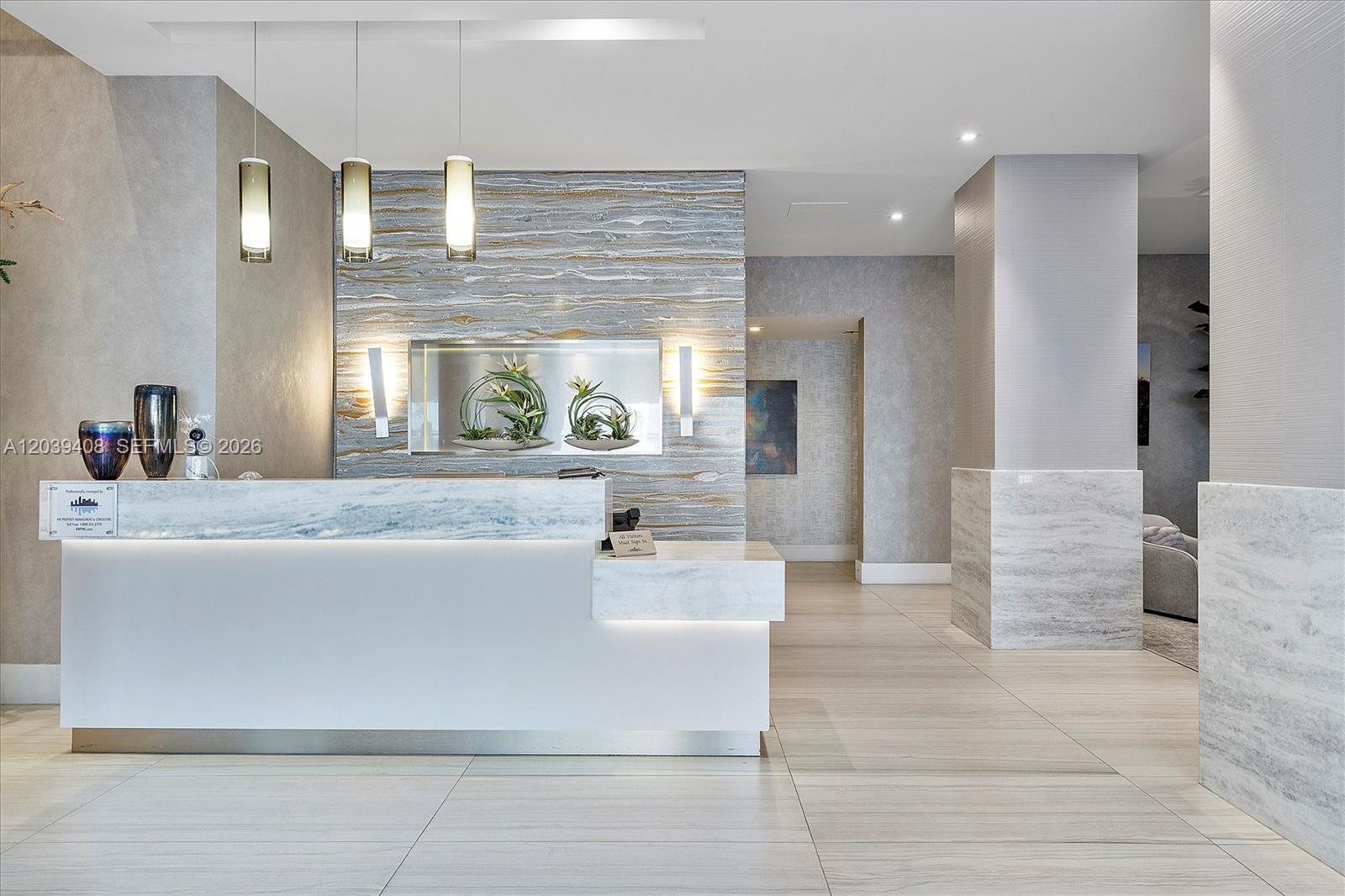 A modern lobby features a marble reception desk, textured stone accent wall, and pendant lighting — 2301 S Ocean Dr # 1406, Hollywood FL 33019, HOLLYWOOD, FL