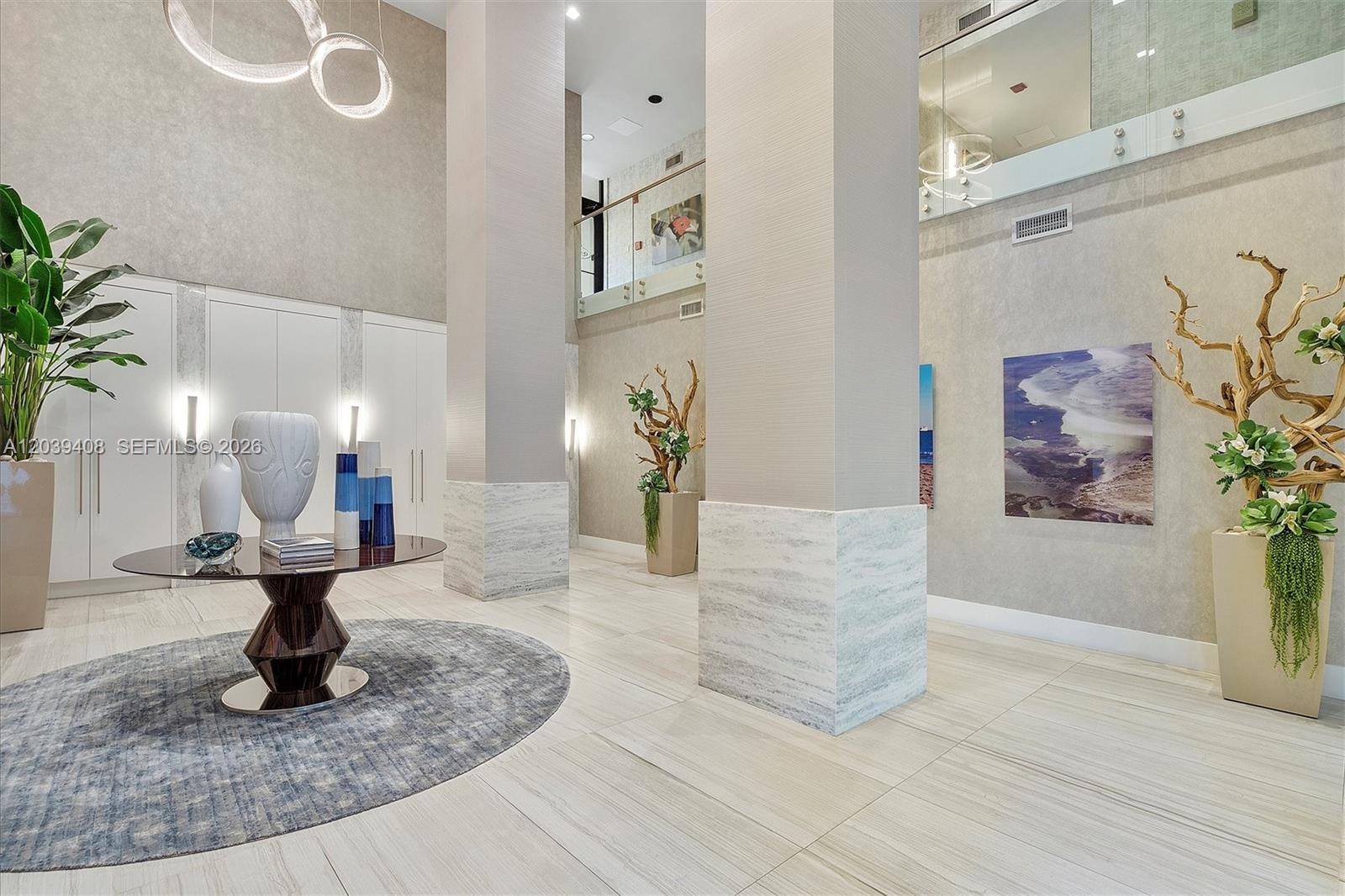 A modern, high-ceilinged lobby features large columns, tiled floors, and decorative floral arrangements — 2301 S Ocean Dr # 1406, Hollywood FL 33019, HOLLYWOOD, FL