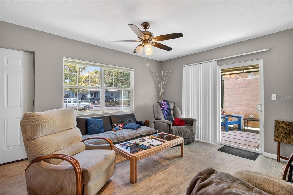 A living room features light wood-look flooring, a ceiling fan, a sofa, and sliding glass doors — 7772 90TH WAY, SEMINOLE, FL
