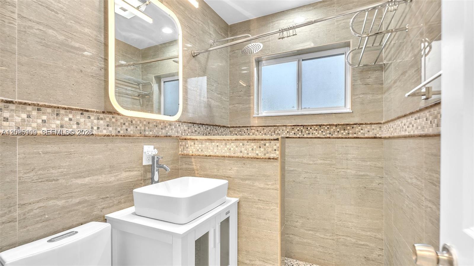 A modern bathroom features a vessel sink, a walk-in shower, and beige tiled walls — 3375 SW 1st St, Miami FL 33135, MIAMI, FL