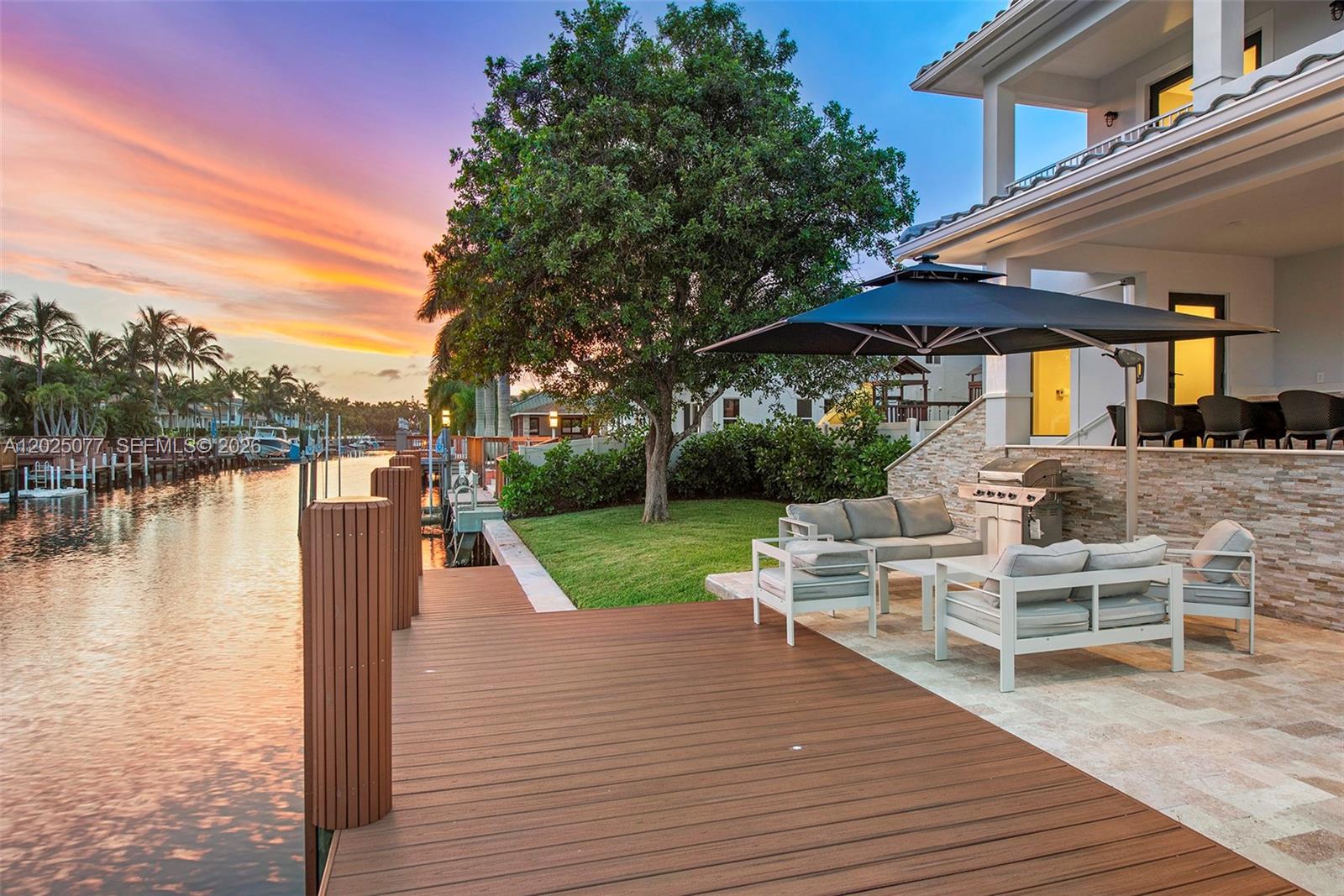A wooden dock sits beside a patio with outdoor furniture and a grill at sunset — 850 Washington St, Hollywood FL 33019, HOLLYWOOD, FL
