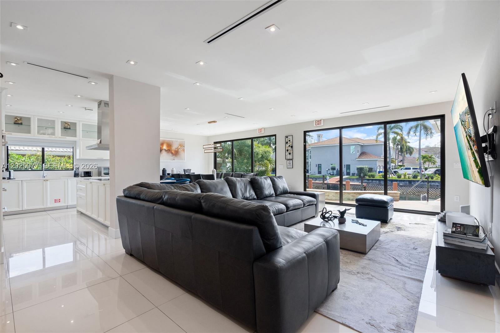 A living room with a large black sectional sofa, tile floors, and sliding glass doors — 850 Washington St, Hollywood FL 33019, HOLLYWOOD, FL