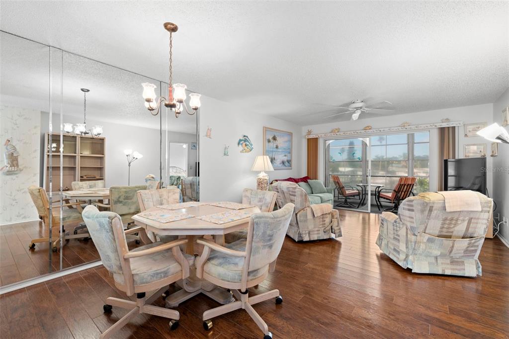 A dining area with a mirrored wall opens into a living room with hardwood floors — 5157 SILENT LOOP UNIT 208, NEW PORT RICHEY, FL