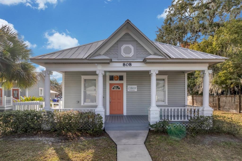 A gray, single-story house with a metal roof, front porch, and a coral-colored front door — 808 MABBETTE STREET, KISSIMMEE, FL