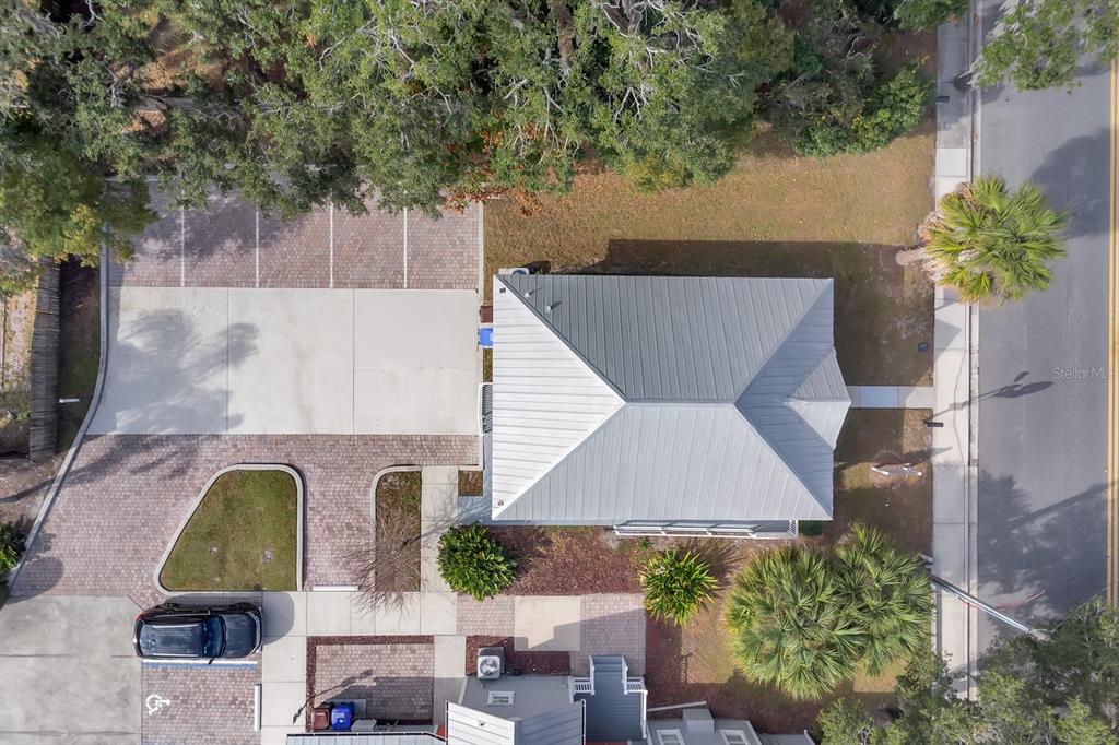 An aerial view shows a building with a metal roof, paved parking, and landscaped grounds — 808 MABBETTE STREET, KISSIMMEE, FL