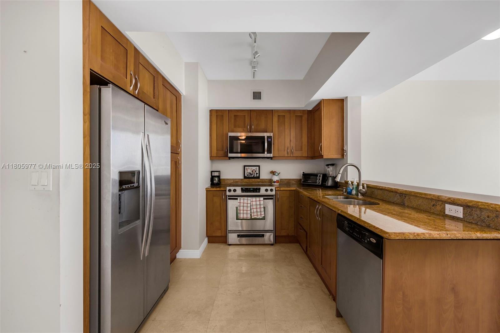 A kitchen features wood cabinets, granite countertops, stainless steel appliances, and tile flooring — 1755 E Hallandale Beach Blvd # 1604E, Hallandale Beach FL 33009, HALLANDALE BEACH, FL