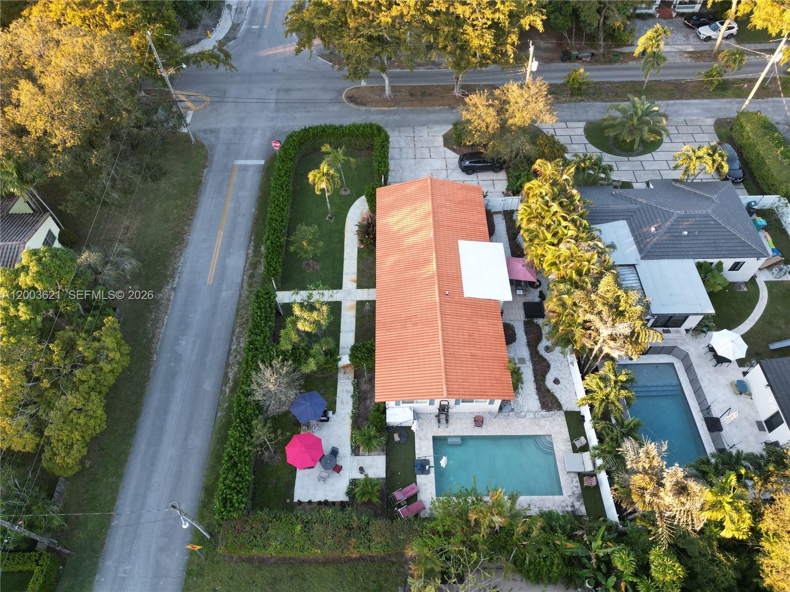 An aerial view shows a house with a terracotta roof, a swimming pool, and landscaping — 12015 NE 7th Ave, Biscayne Park FL 33161, BISCAYNE PARK, FL