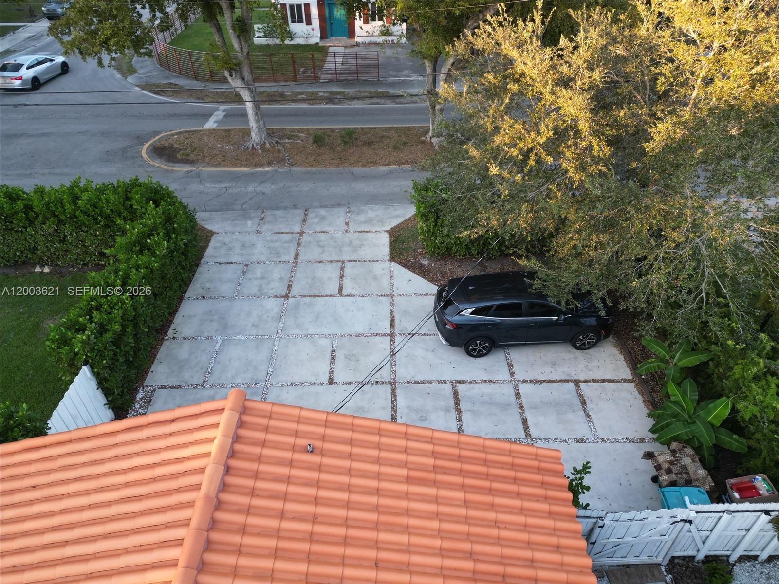 An aerial view shows a concrete driveway with gravel grid accents and a parked car — 12015 NE 7th Ave, Biscayne Park FL 33161, BISCAYNE PARK, FL