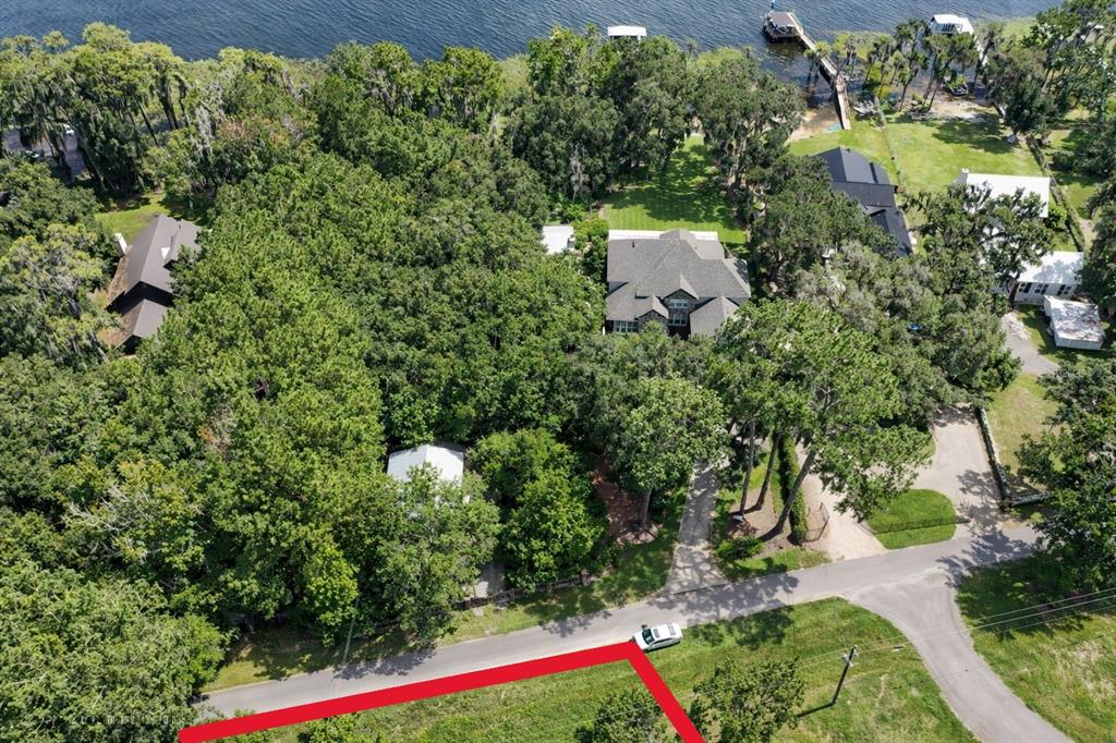 An aerial view shows a wooded residential lot with a house near a lake — 21103 NE 117TH AVENUE, WALDO, FL