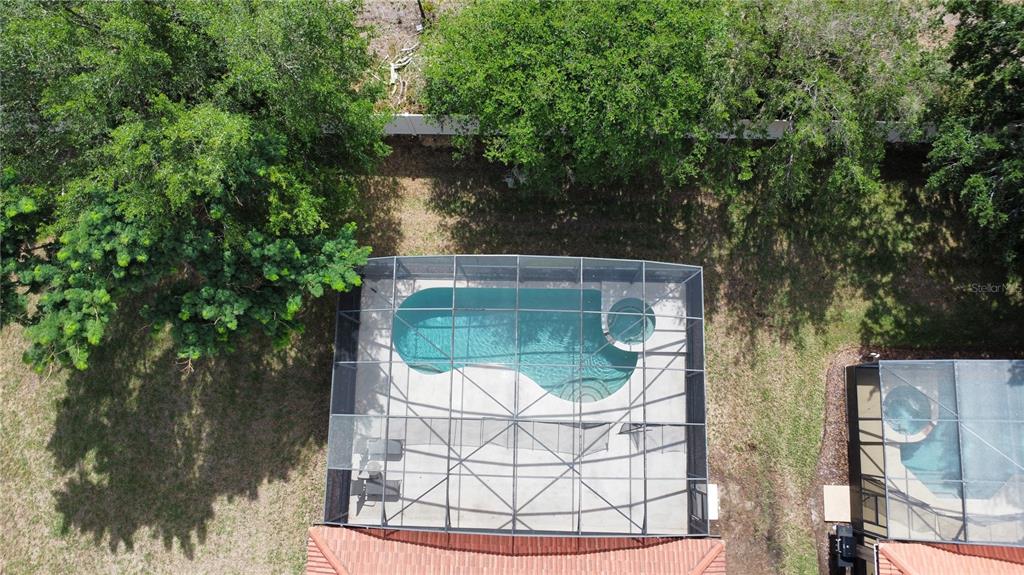 An aerial view shows a screened-in swimming pool and spa behind a residential home — 1162 SOLANA CIRCLE, DAVENPORT, FL