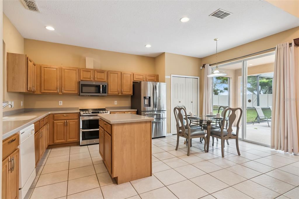 A kitchen with light wood cabinets, stainless steel appliances, a center island, and tile flooring — 1162 SOLANA CIRCLE, DAVENPORT, FL