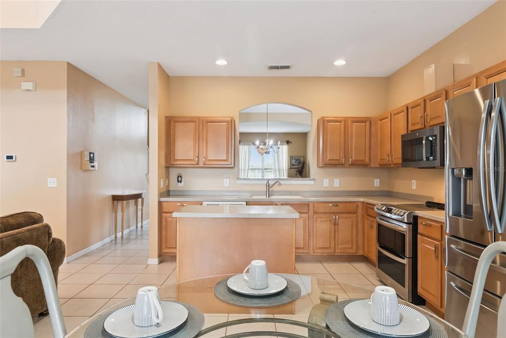 A kitchen features light wood cabinets, stainless steel appliances, and a central island — 1162 SOLANA CIRCLE, DAVENPORT, FL