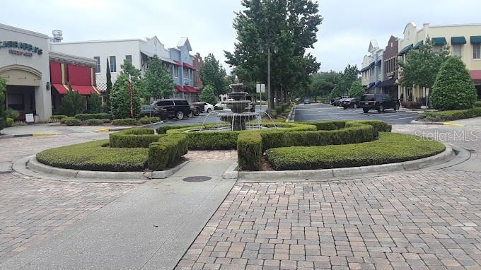 A tiered stone fountain sits in the center of a landscaped roundabout with brick paving — 16540 POINTE VILLAGE DRIVE UNIT 206, LUTZ, FL