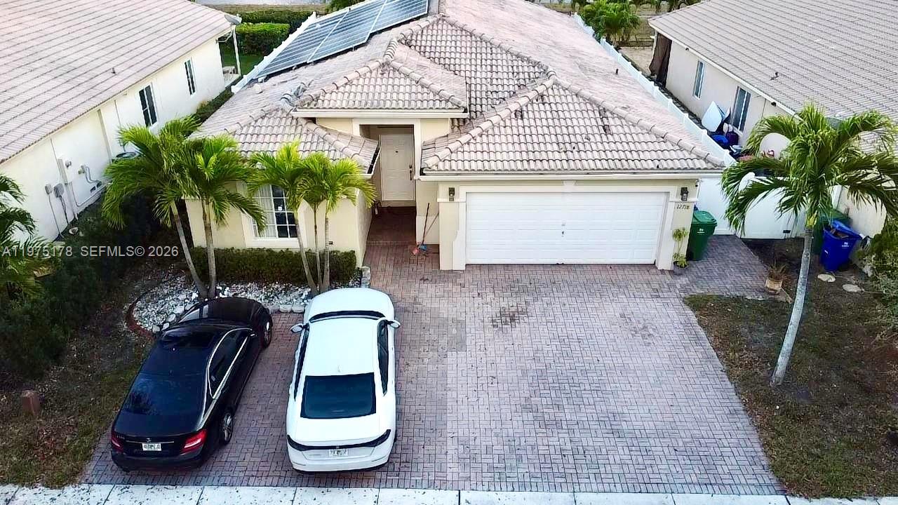 An aerial view shows a single-story house with a tiled roof, garage, and paved driveway — 12718 SW 47th St, Miramar FL 33027, MIRAMAR, FL