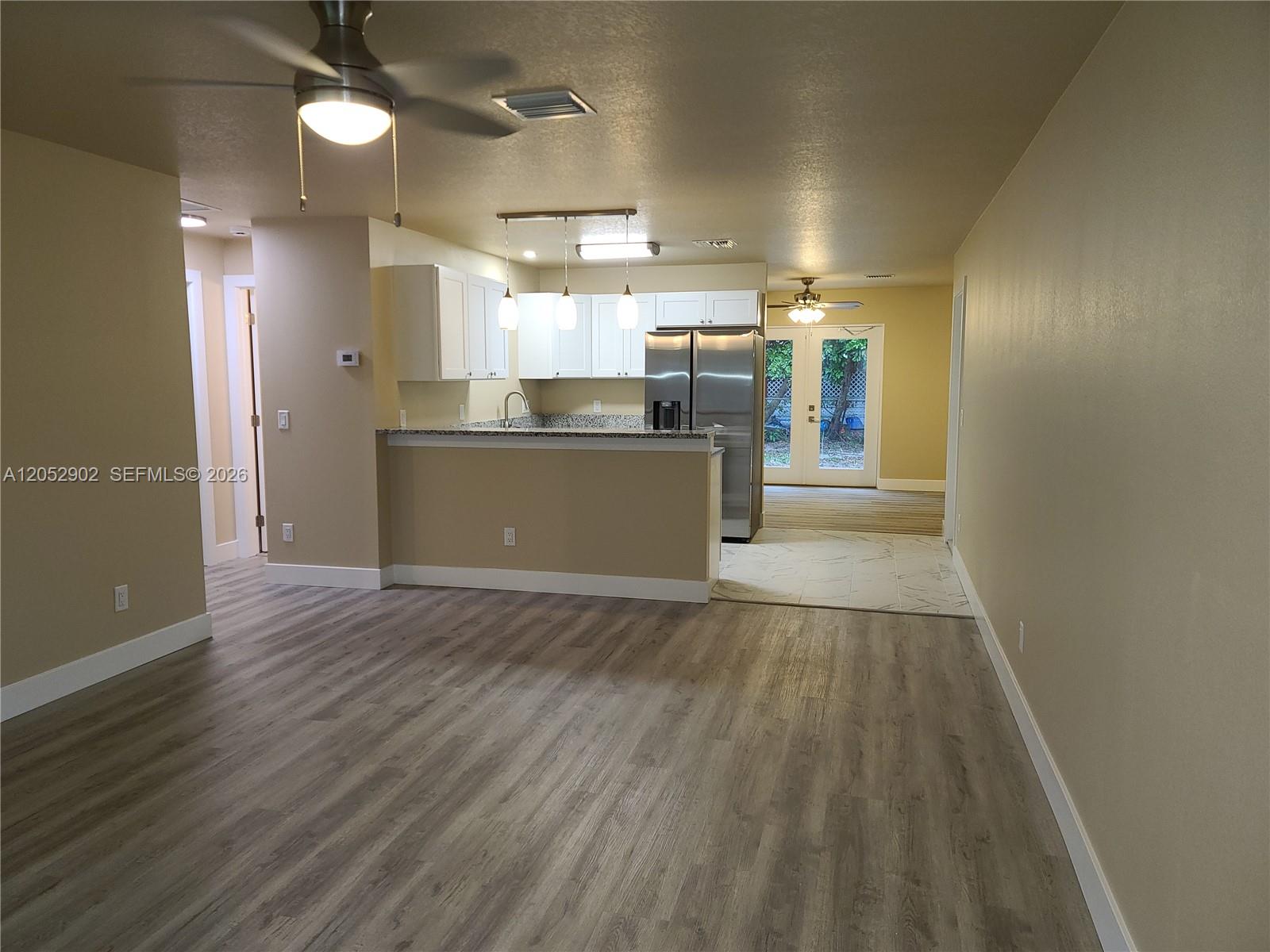 An open-concept kitchen with white cabinets and stainless steel appliances overlooks a living area — 4491 SE Roaring Brook Way # 4491, Stuart FL 34997, STUART, FL