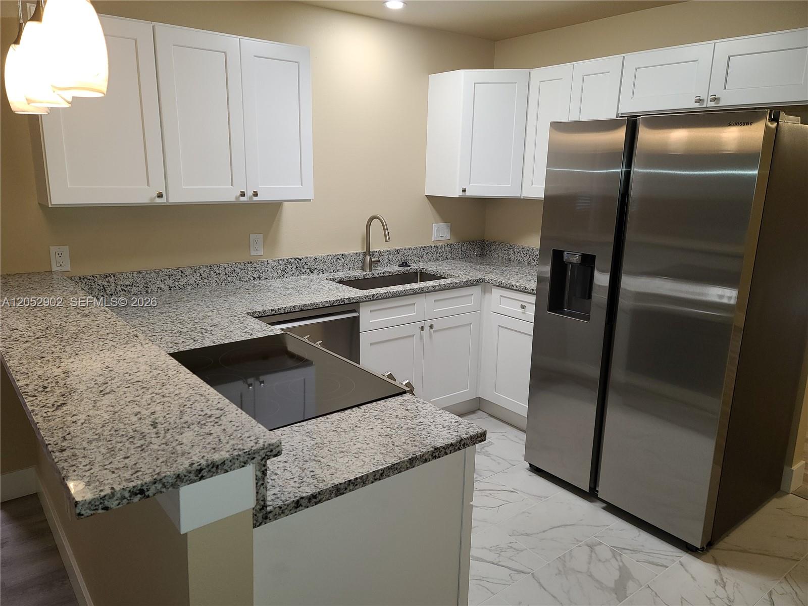 A kitchen features white cabinets, granite countertops, stainless steel appliances, and light-colored tile flooring — 4491 SE Roaring Brook Way # 4491, Stuart FL 34997, STUART, FL