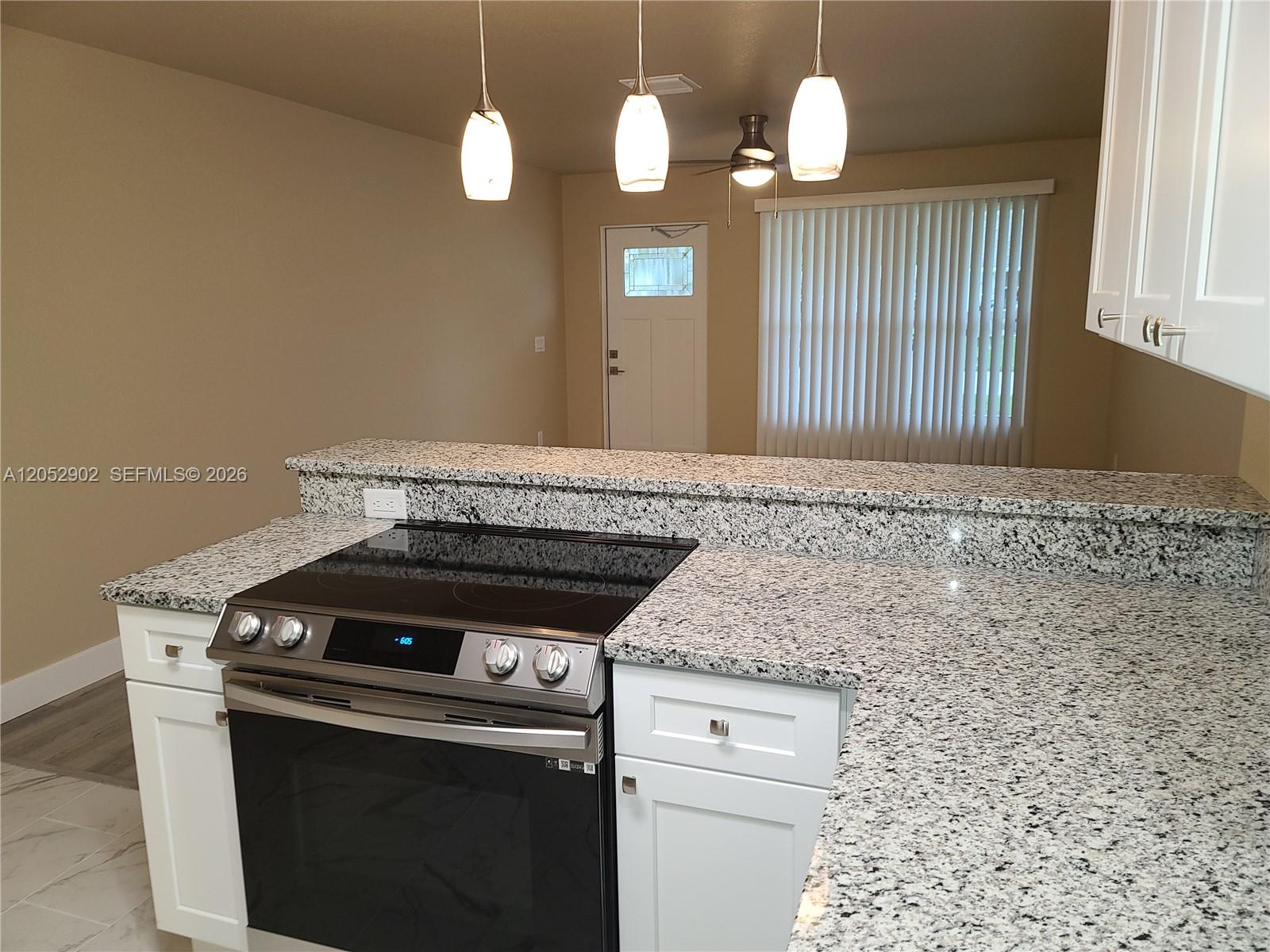 A kitchen features white cabinets, granite countertops, a stainless steel stove, and pendant lighting — 4491 SE Roaring Brook Way # 4491, Stuart FL 34997, STUART, FL