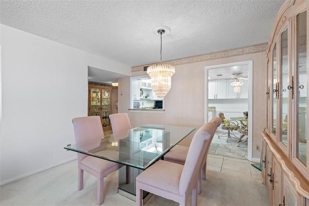 A dining room features a glass-top table, pink upholstered chairs, and a crystal chandelier — 1430 GULF BOULEVARD UNIT 501, CLEARWATER BEACH, FL