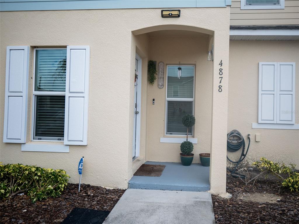 The exterior of a beige house features a front entrance with a small porch area — 4878 CORAL CASTLE DRIVE, KISSIMMEE, FL