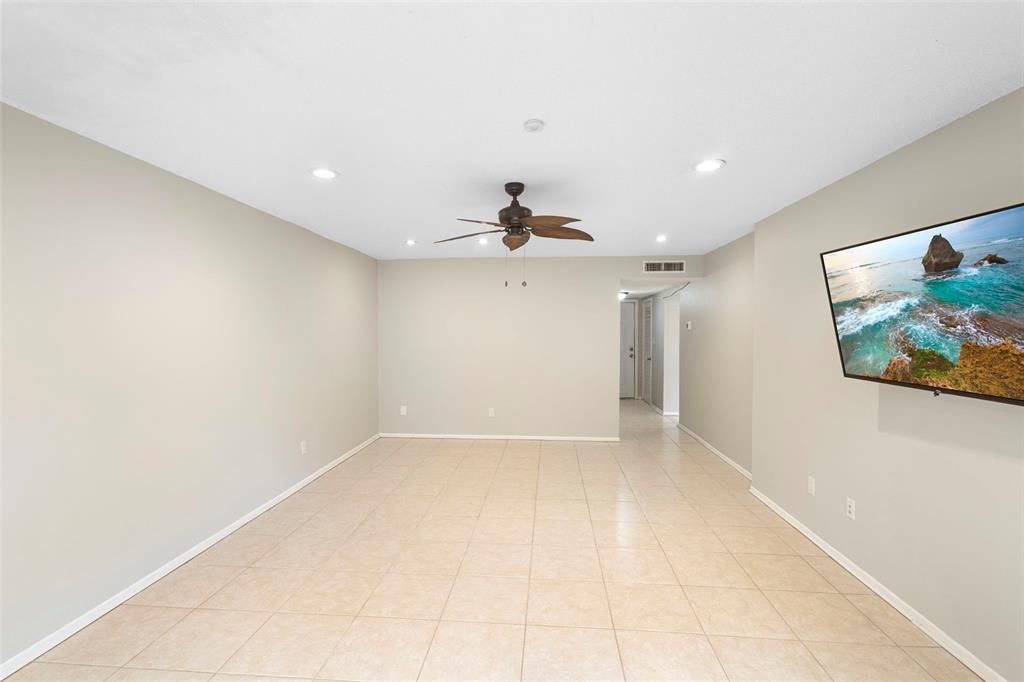 An empty living room features light-colored tile flooring, beige walls, and a ceiling fan — 7471 CANFORD COURT UNIT 19, WINTER PARK, FL