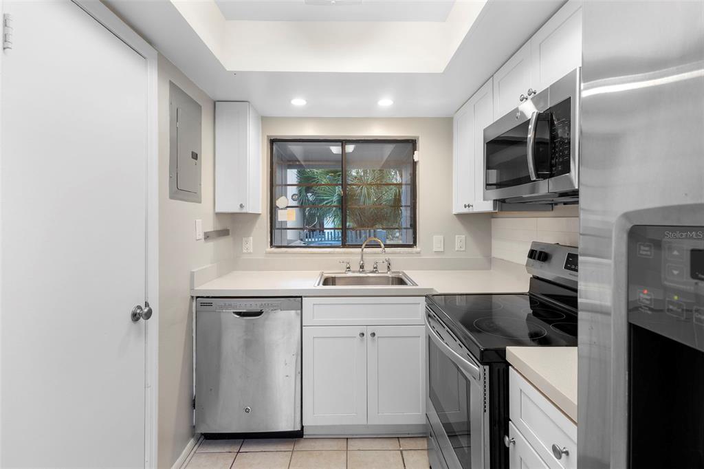 A kitchen with white cabinets, stainless steel appliances, a window, and tile flooring — 7471 CANFORD COURT UNIT 19, WINTER PARK, FL