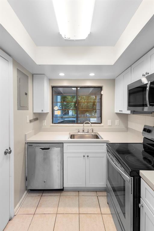 A kitchen features white cabinets, stainless steel appliances, a sink, and light-colored tile flooring — 7471 CANFORD COURT UNIT 19, WINTER PARK, FL