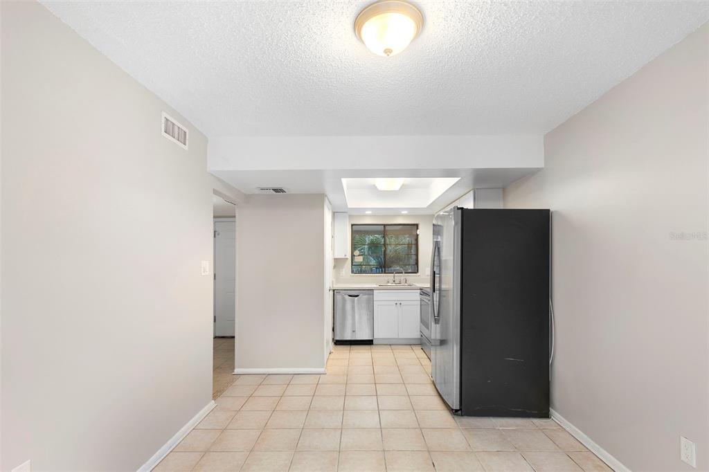 A kitchen with tile flooring, white cabinets, stainless steel appliances, and a black refrigerator — 7471 CANFORD COURT UNIT 19, WINTER PARK, FL