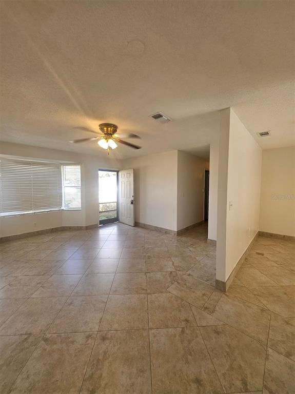 A living room features beige tile flooring, a ceiling fan, and a front entry door — 1225 ARMSDALE AVENUE, PORT CHARLOTTE, FL