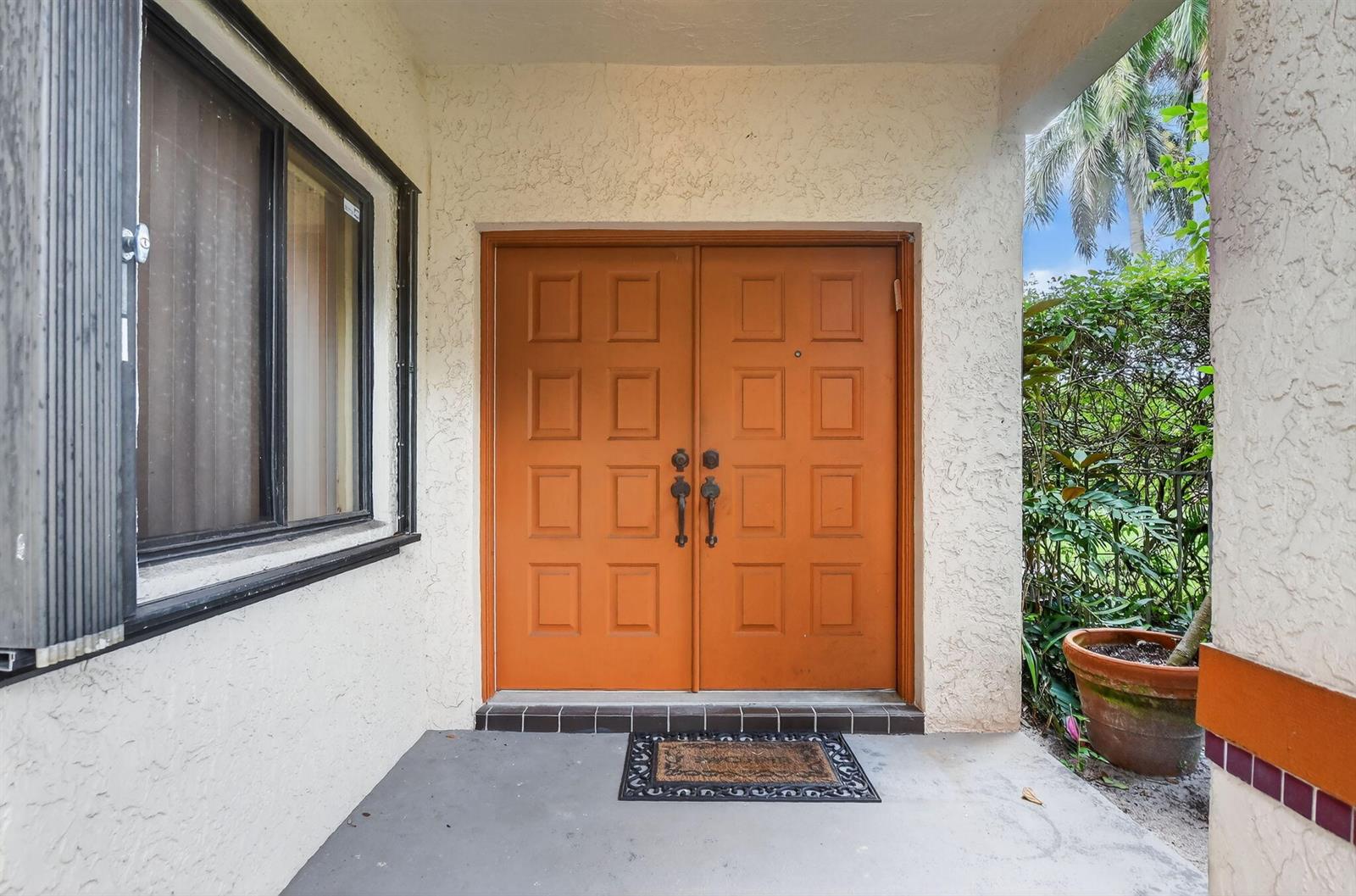 A front entryway features double orange doors with recessed panels and a concrete porch — 20803 Cabrillo Way, Boca Raton FL 33428, BOCA RATON, FL