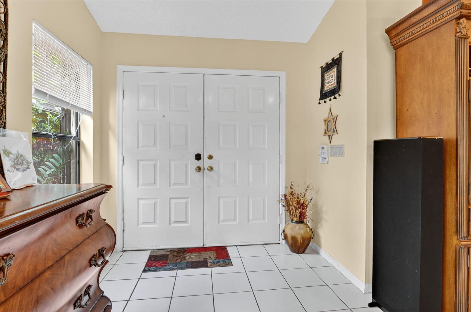A foyer features white tile flooring, double entry doors, and a wooden dresser — 20803 Cabrillo Way, Boca Raton FL 33428, BOCA RATON, FL