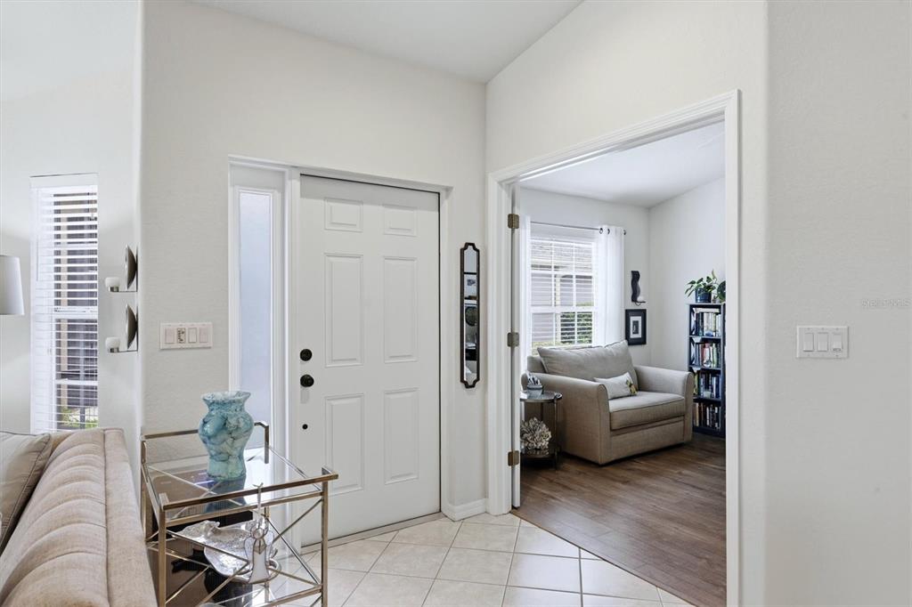 A white front door opens into a tiled entryway next to a room with wood flooring — 3518 LAKEWOOD BOULEVARD, NORTH PORT, FL