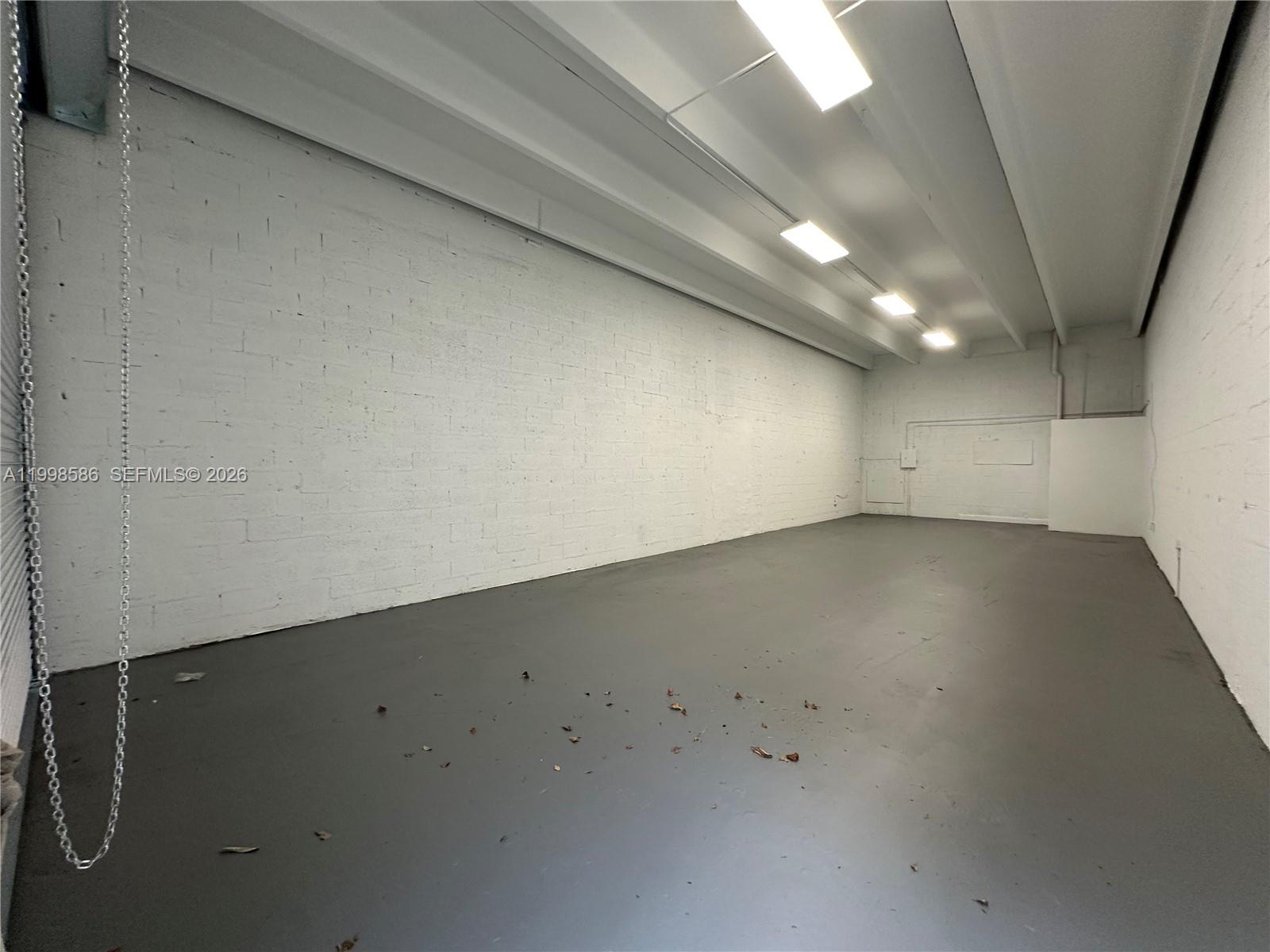 An empty industrial space features white painted brick walls, a gray floor, and overhead lighting — 5818 SW 25th St # 2, West Park FL 33023, WEST PARK, FL