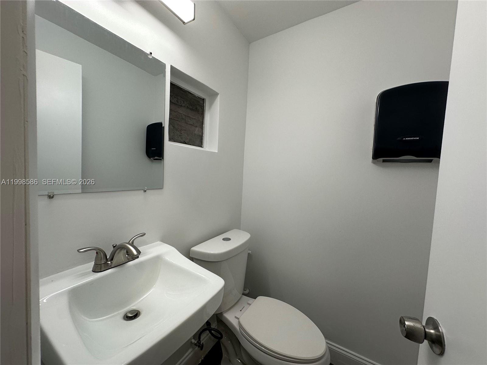 A small bathroom features a white pedestal sink, a toilet, and a wall-mounted paper dispenser — 5818 SW 25th St # 2, West Park FL 33023, WEST PARK, FL