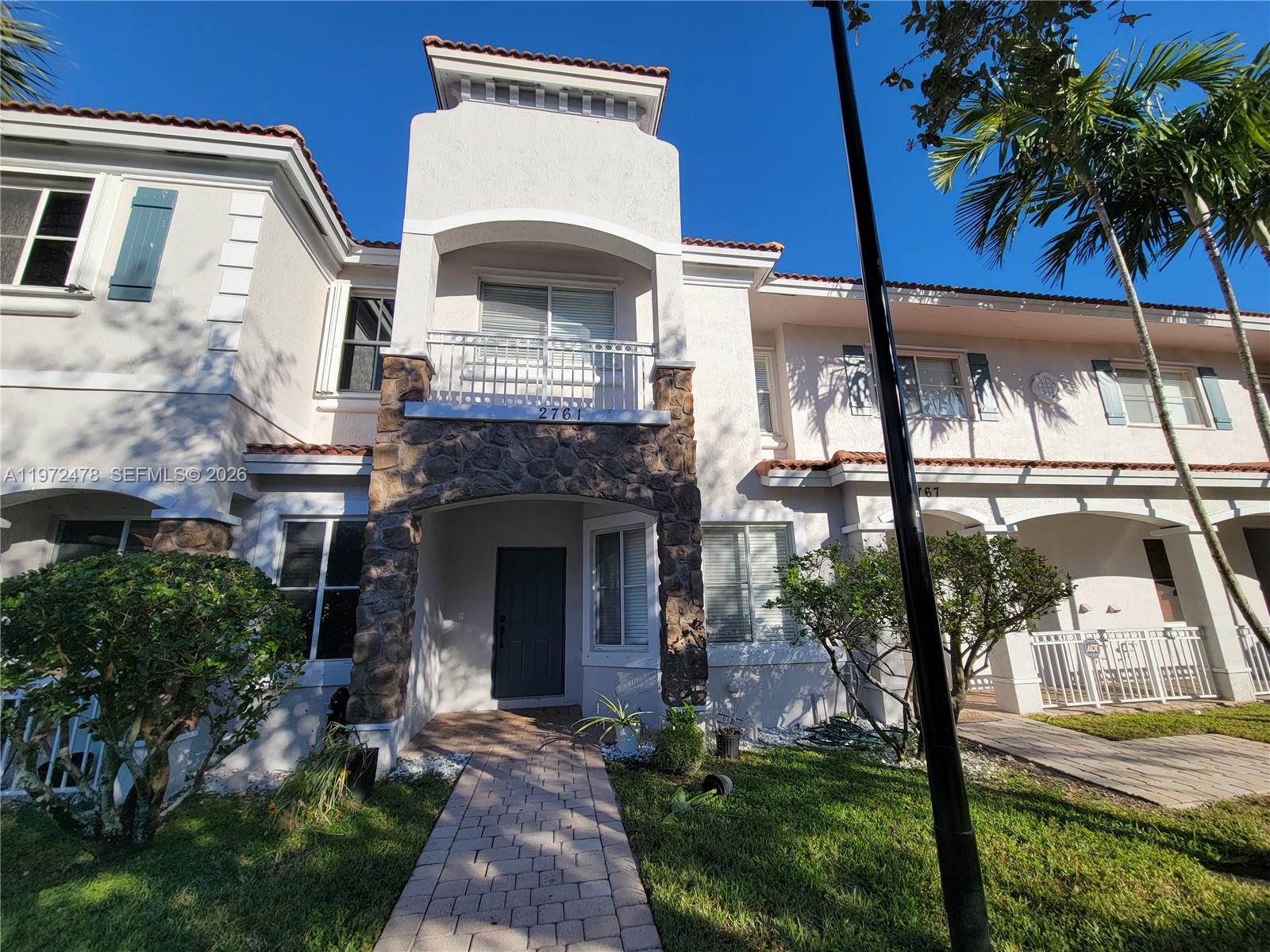 A two-story townhouse exterior features a stone-accented entryway, a balcony, and a paved walkway — 2761 SW 82nd Ave # 102, Miramar FL 33025, MIRAMAR, FL