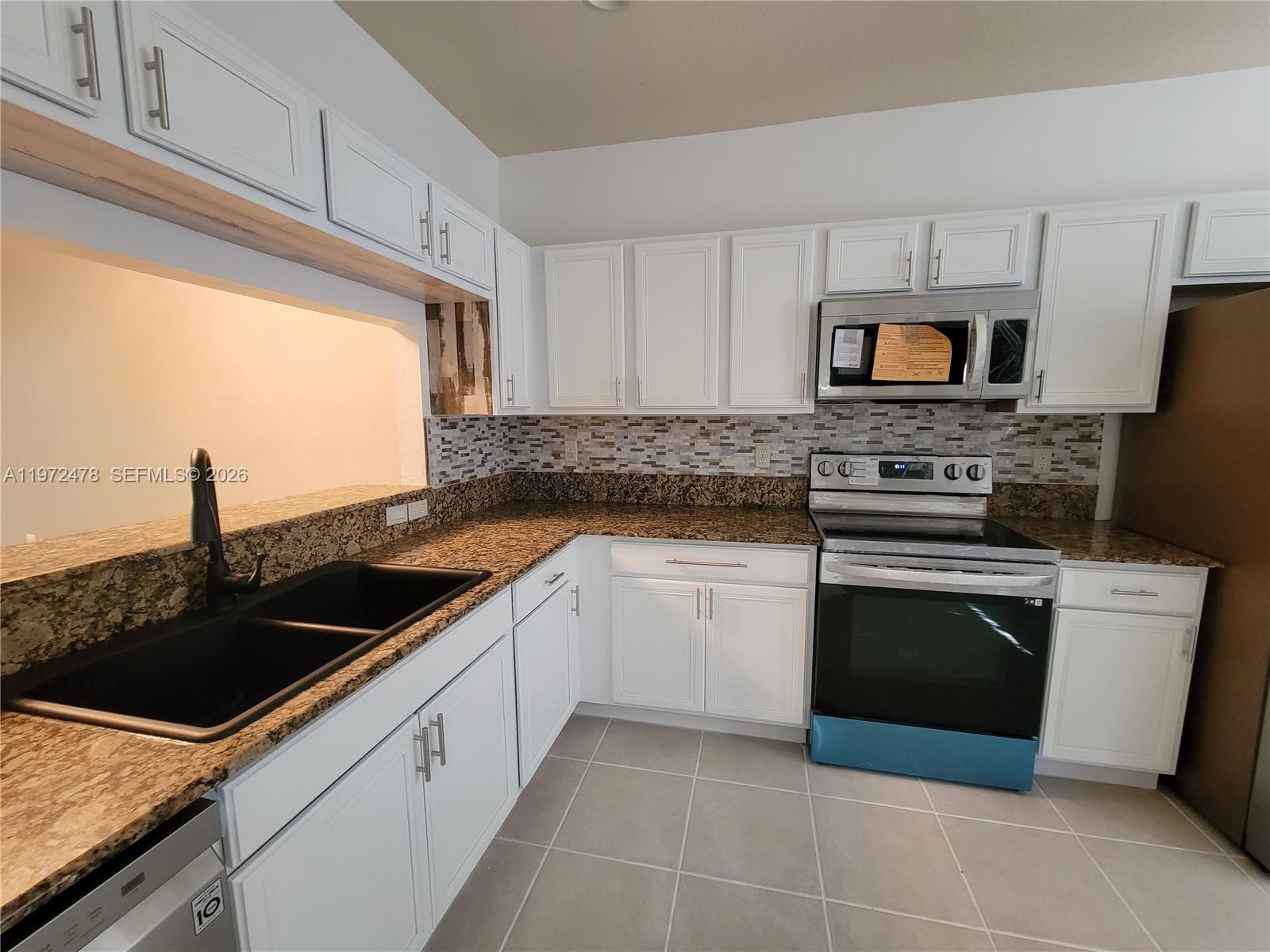 A kitchen features white cabinets, granite countertops, a black sink, and stainless steel appliances — 2761 SW 82nd Ave # 102, Miramar FL 33025, MIRAMAR, FL