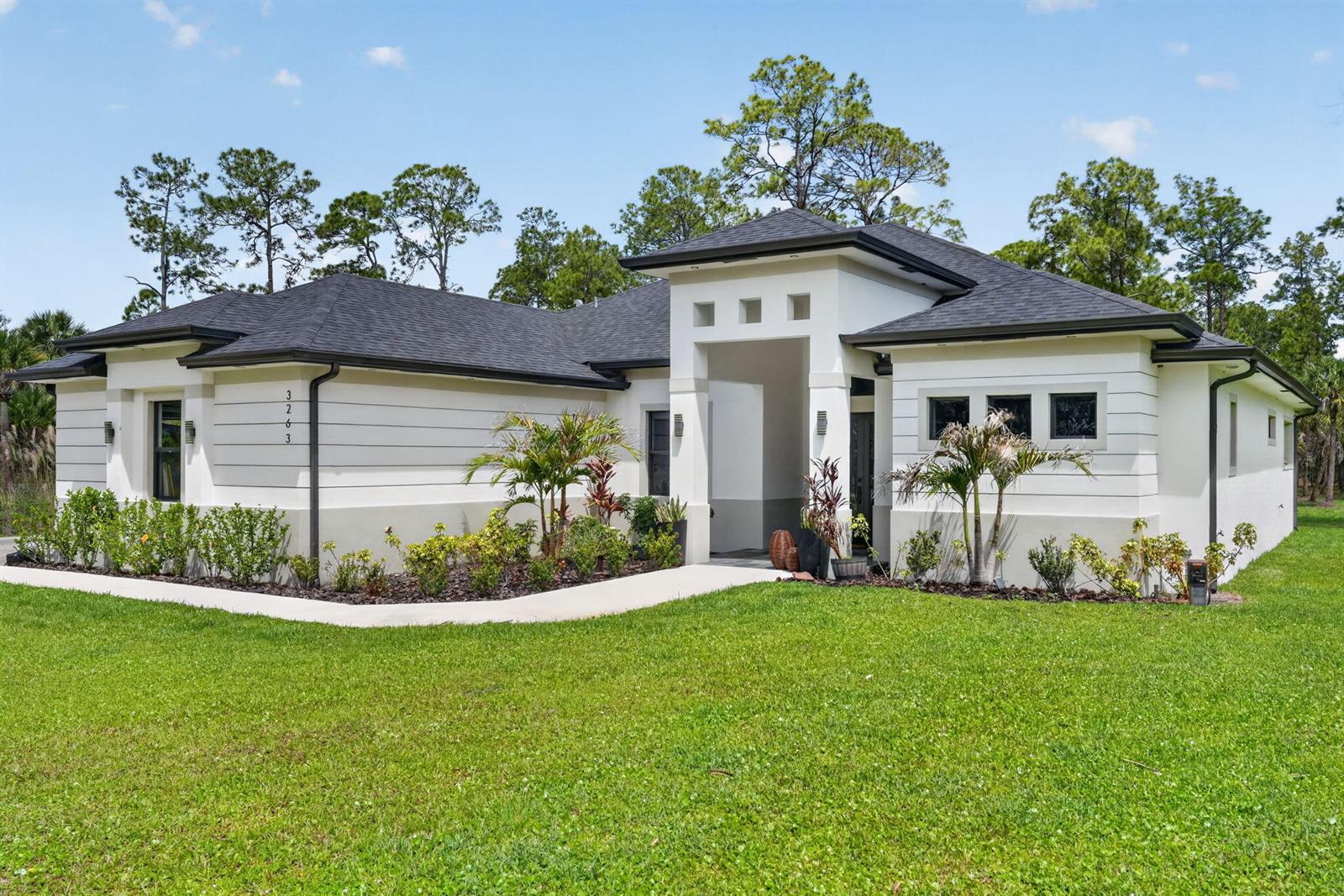 A single-story house with white horizontal siding, a dark roof, and a central entryway — 3263 SE 40th Ave Avenue SE, Naples FL 34117, NAPLES, FL