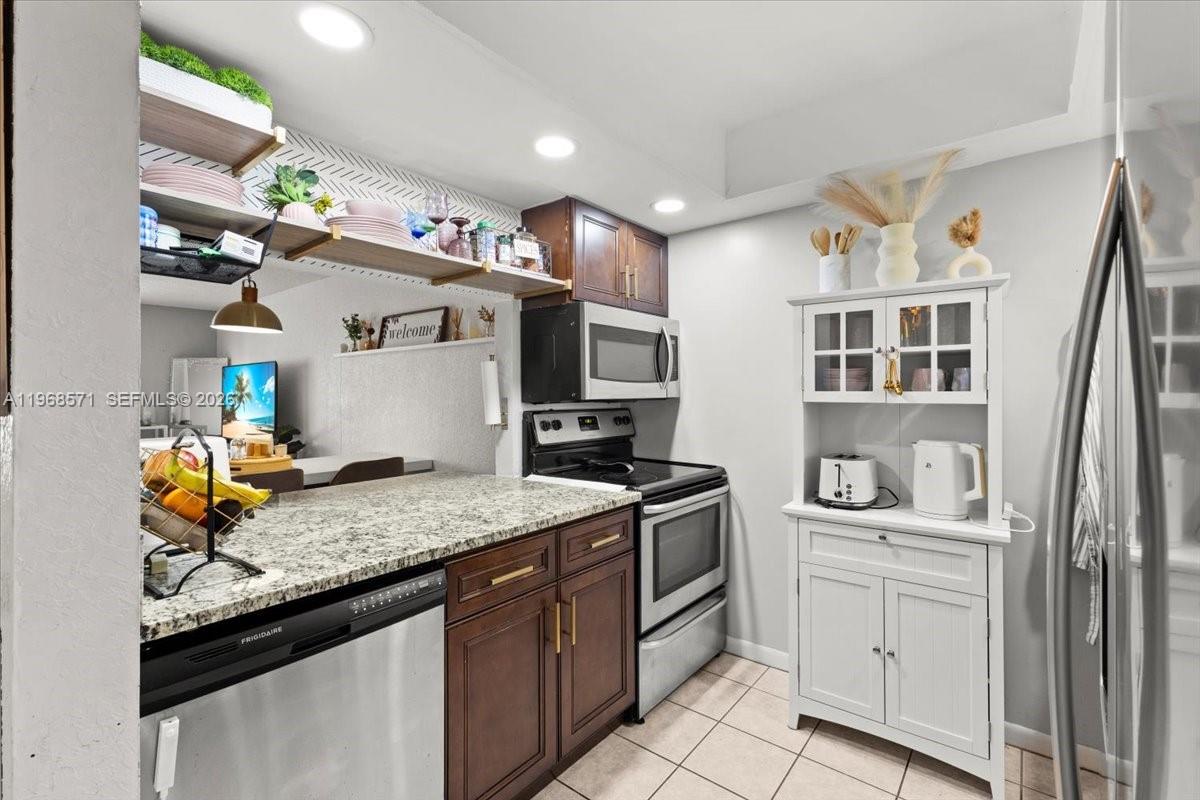 A kitchen features dark wood cabinets, granite countertops, stainless steel appliances, and a white hutch — 307 Waterside Dr, Hypoluxo FL 33462, HYPOLUXO, FL