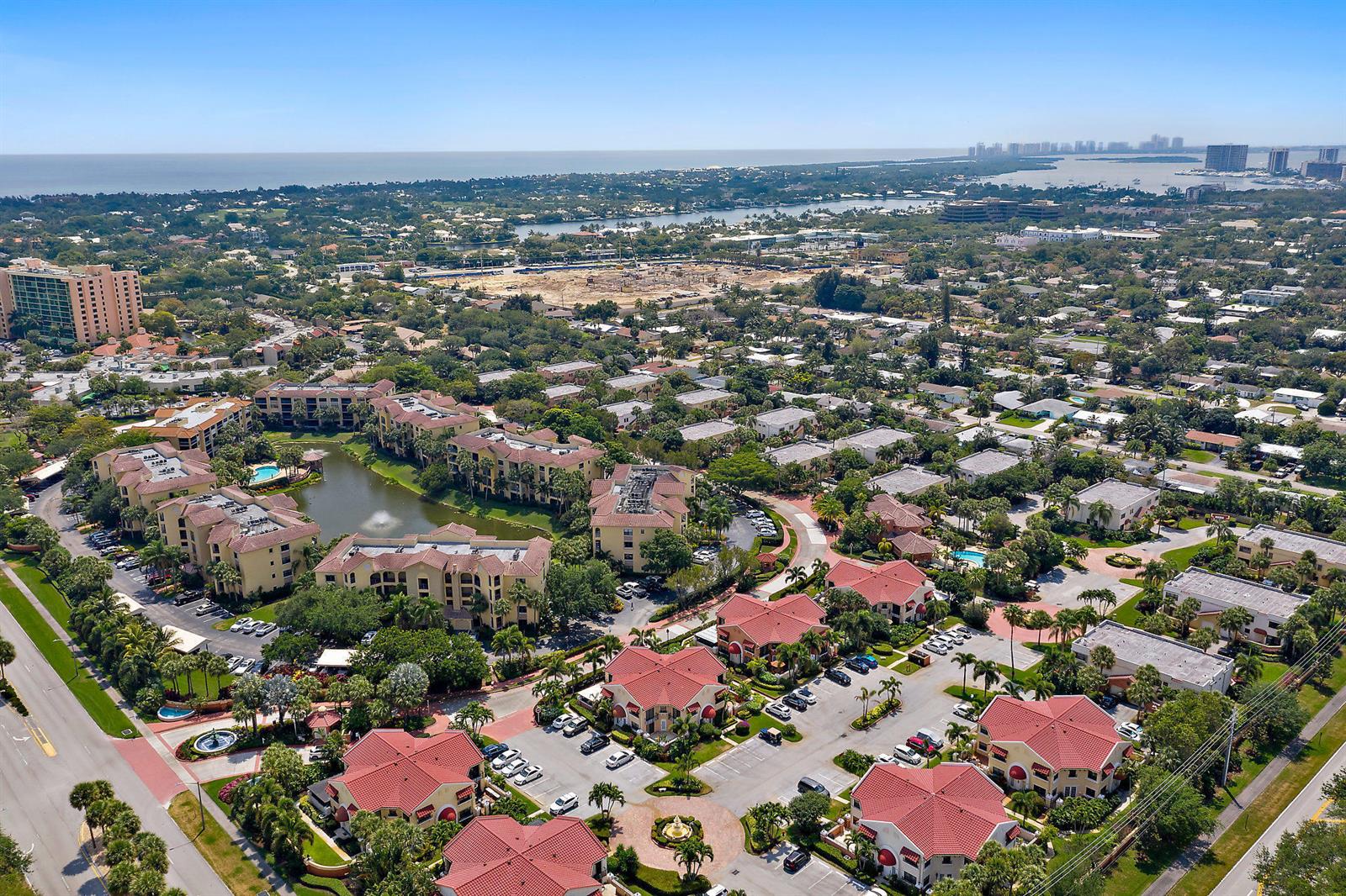 An aerial view shows a residential complex with red-roofed buildings, a pond, and parking — 13 Uno Lago Drive, Juno Beach FL 33408, JUNO BEACH, FL
