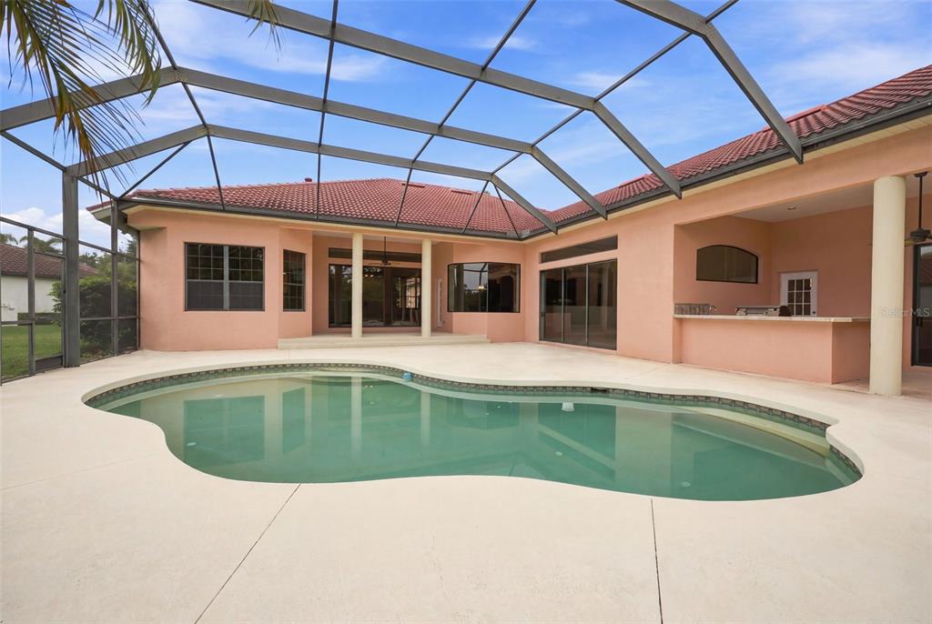 A screened-in patio features a swimming pool, a covered lanai, and a built-in outdoor bar — 10609 CHEVAL PLACE, BRADENTON, FL