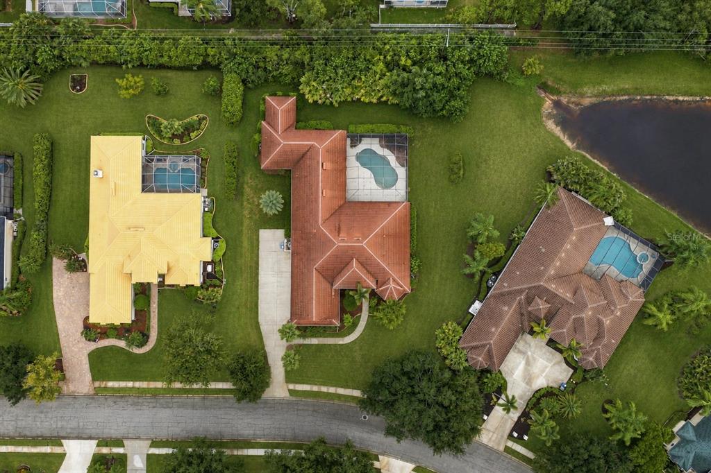 An aerial view shows three suburban houses with swimming pools and tiled roofs — 10609 CHEVAL PLACE, BRADENTON, FL