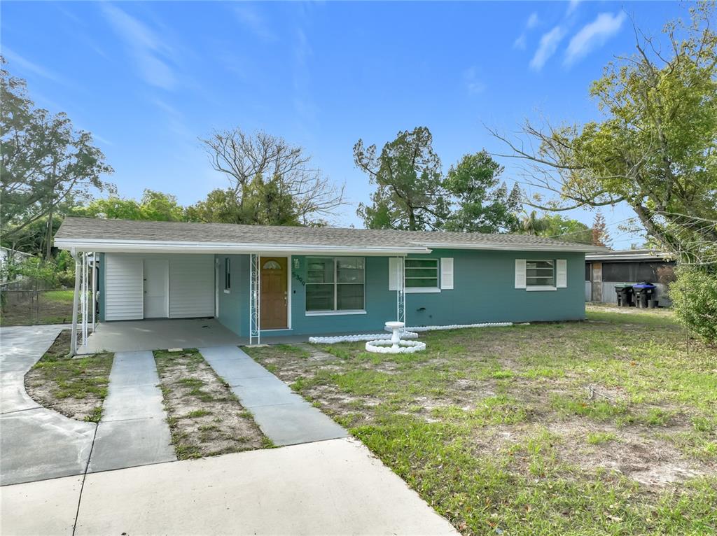 A single-story teal house with a carport and a concrete driveway under a blue sky — 5399 PALADIN WAY, ORLANDO, FL