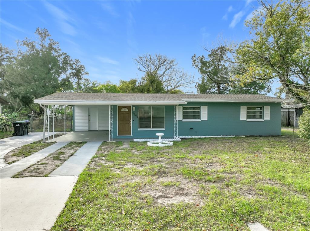 A single-story teal house with a carport, white shutters, and a concrete driveway — 5399 PALADIN WAY, ORLANDO, FL