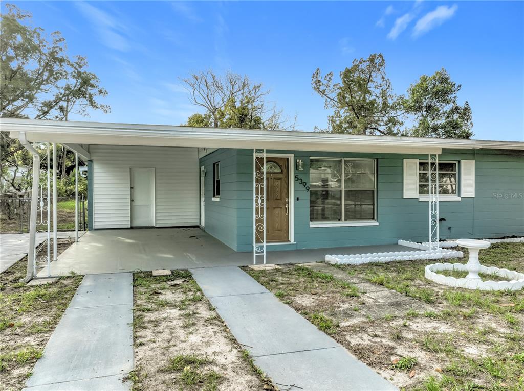 A single-story house with teal siding, a white carport, and a front lawn — 5399 PALADIN WAY, ORLANDO, FL