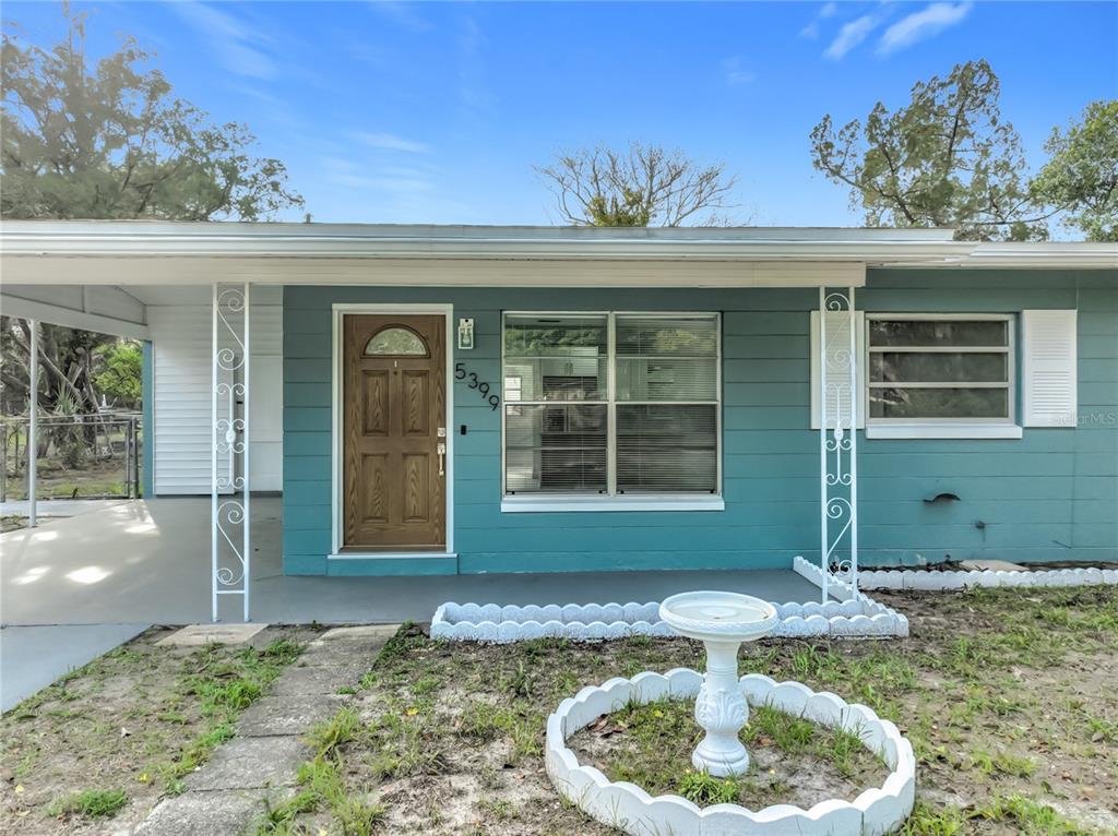 A teal single-story house features a brown front door, white metal porch columns, and a fountain — 5399 PALADIN WAY, ORLANDO, FL